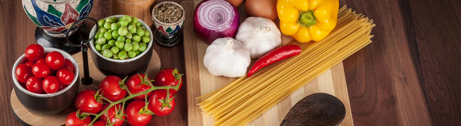vegetables and spaghetti on a wood cutting board